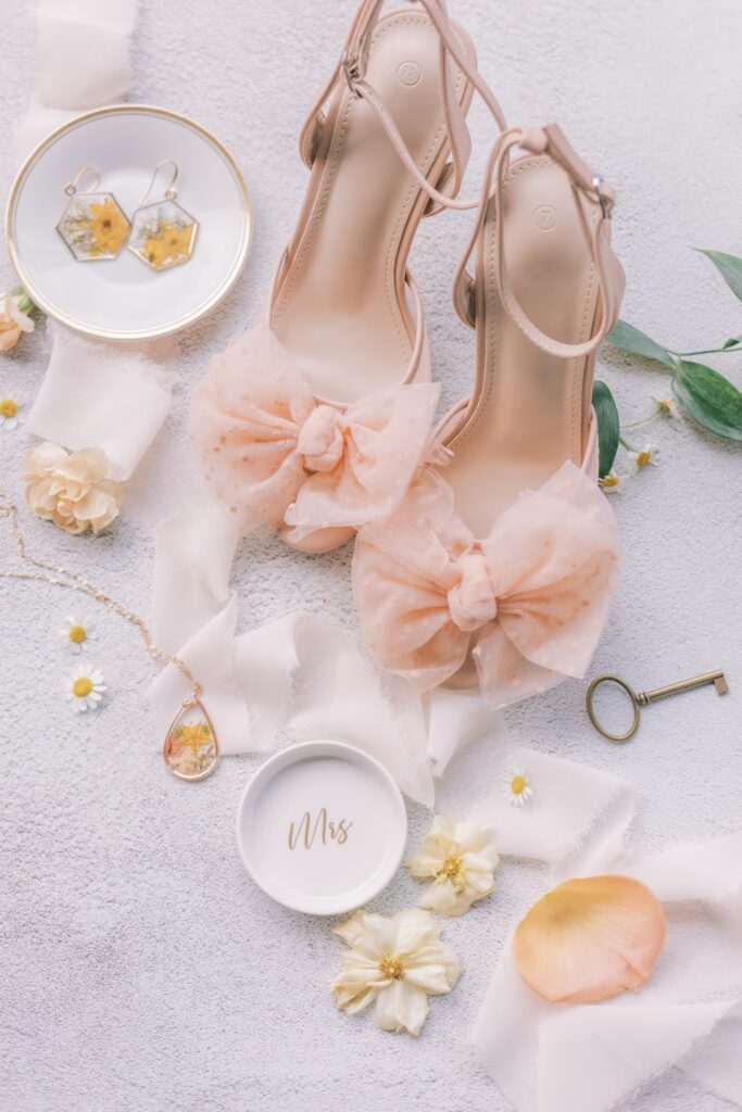 Closeup details shot of bride's shoes in peach fuzz color and necklace featuring a yellow floral. All consistent with summer garden party peach fuzz tone.