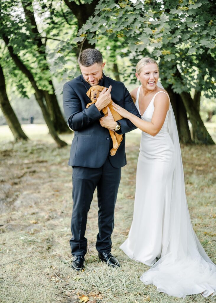 Wedding portrait of couple holding a puppy