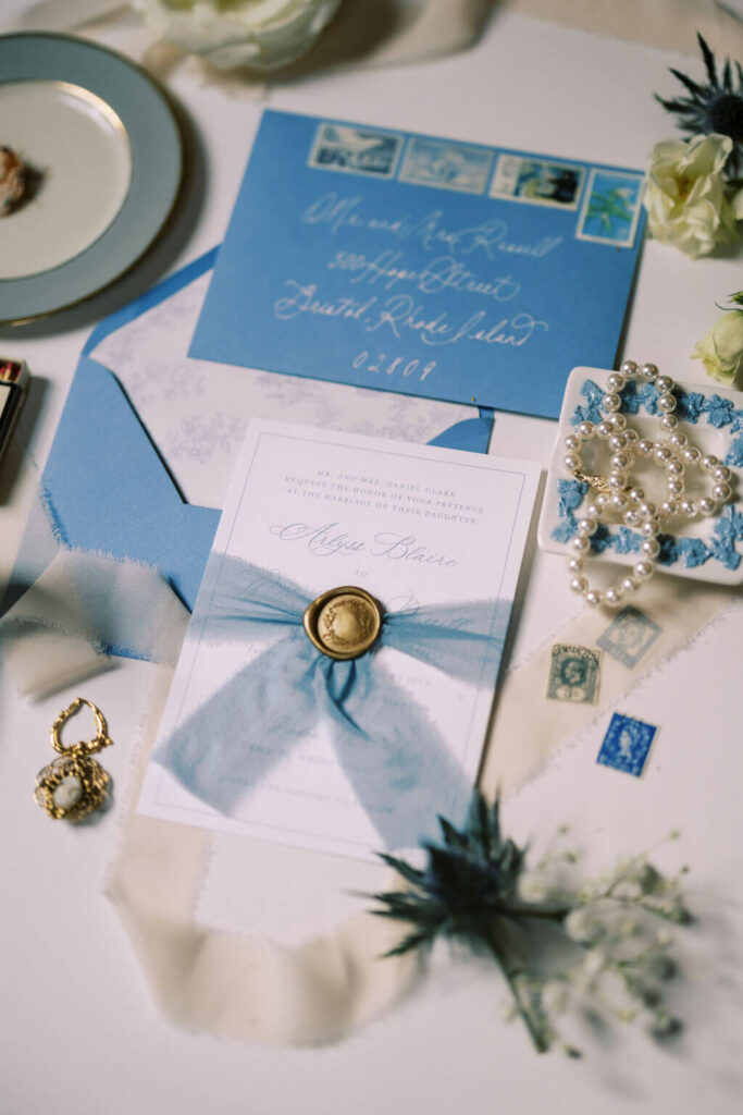 A vintage blue wedding invitation suite with gold wax seal and floral envelope liner