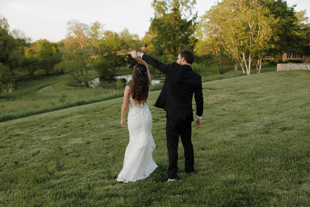 A groom twirls his bride in a meadow at The Farm at Eagles Ridge