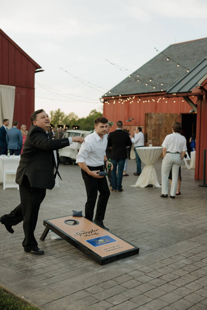 Wedding guests playing cornhole on the patio during a wedding reception at The Farm at Eagles Ridge