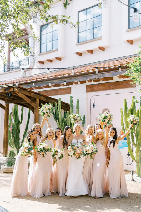 Bride with bridesmaids wearing light pink at an outdoor wedding 