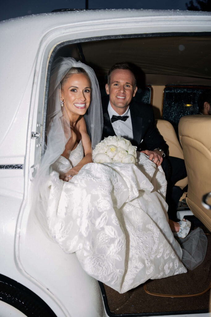 Bride and groom leaving reception in classic car