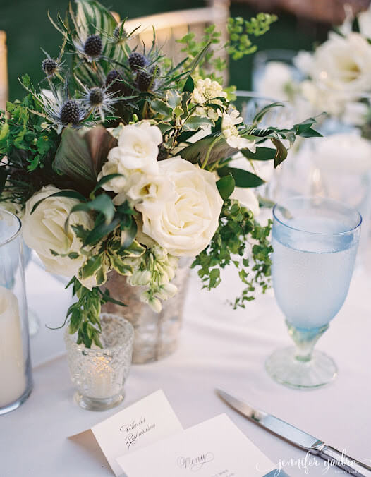 Elegant outdoor tablescape featuring white florals with greenery 