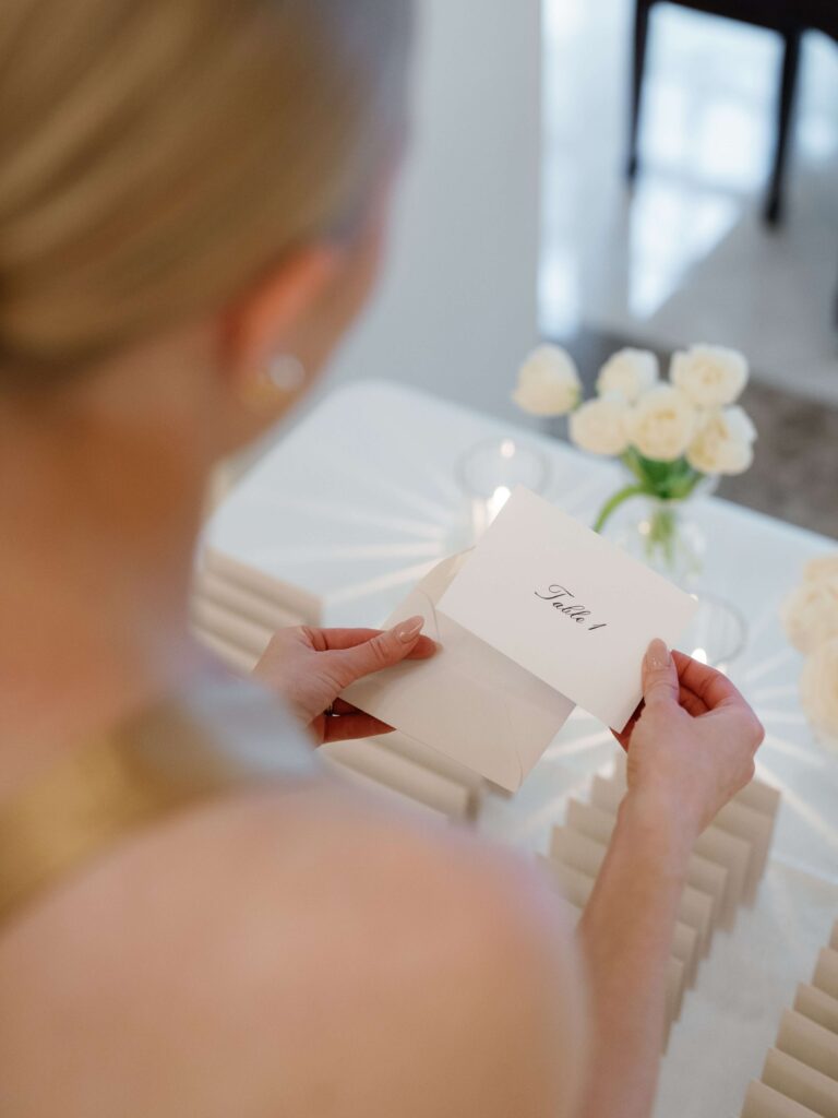 A wedding guest opens an escort card envelope revealing that she is seated at table 1