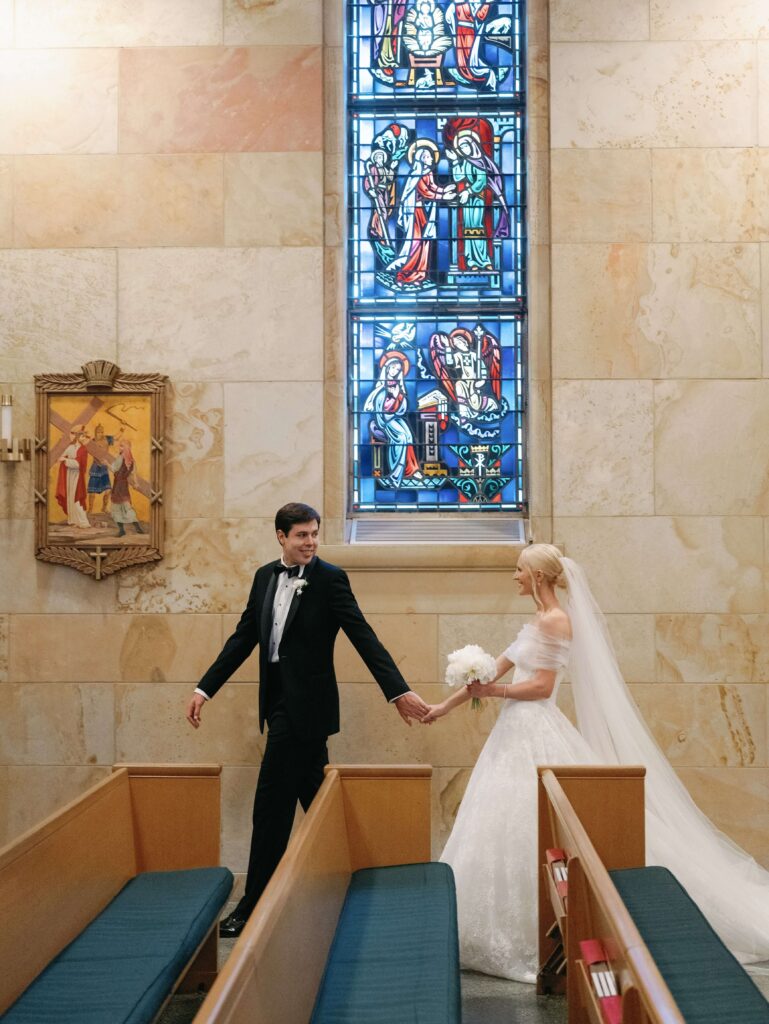 Bride and groom walking in Catholic church holding hands