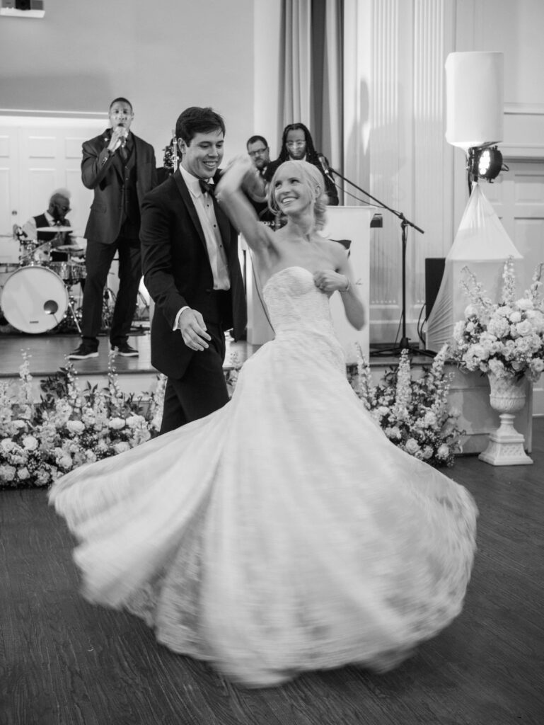 Groom twirling bride during first dance as band sings in background