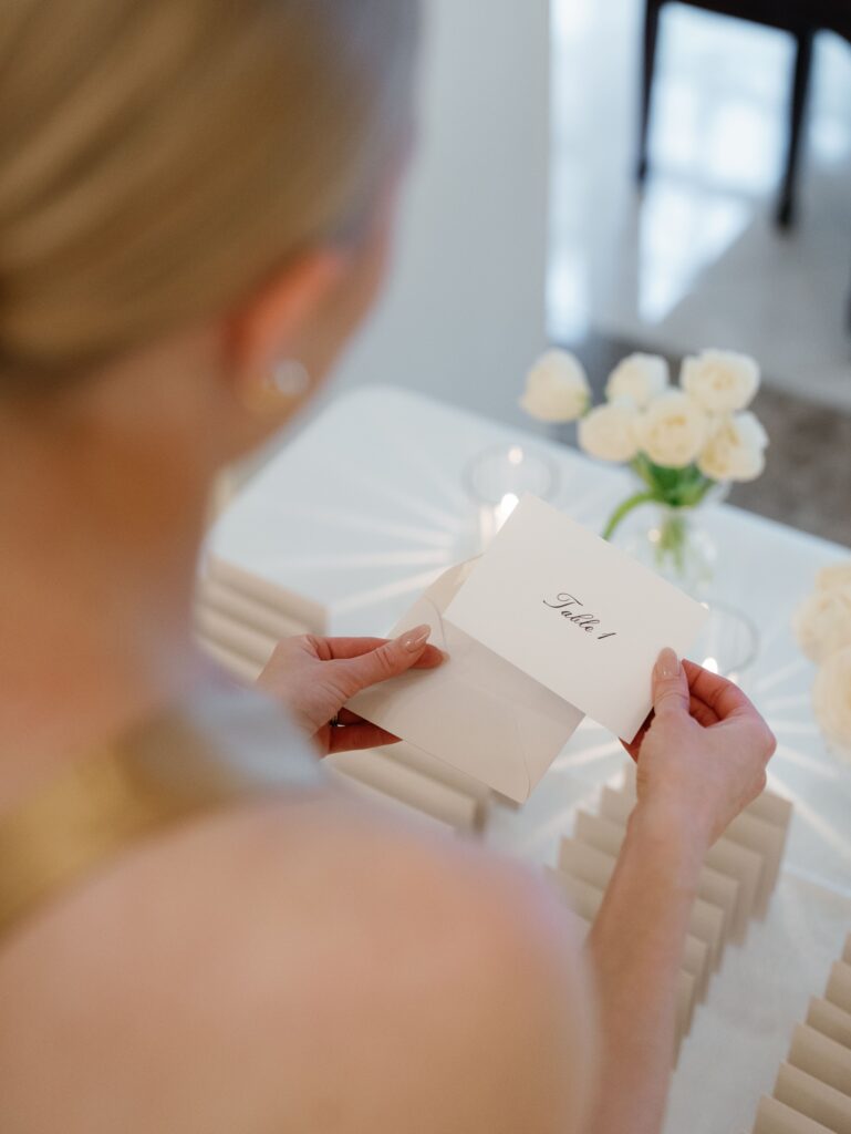Wedding guest holding escort card listing the table number