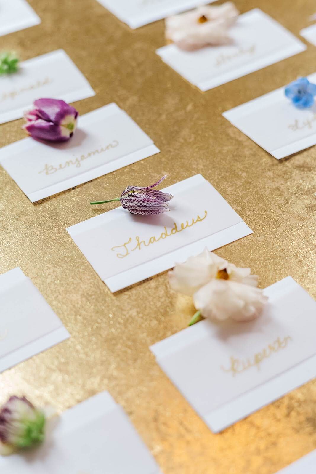Gold calligraphy place cards with flowers