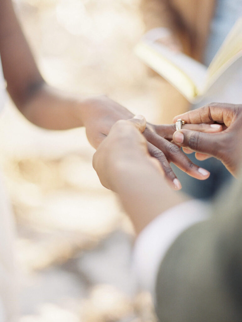 Groom placing ring on bride's finger
