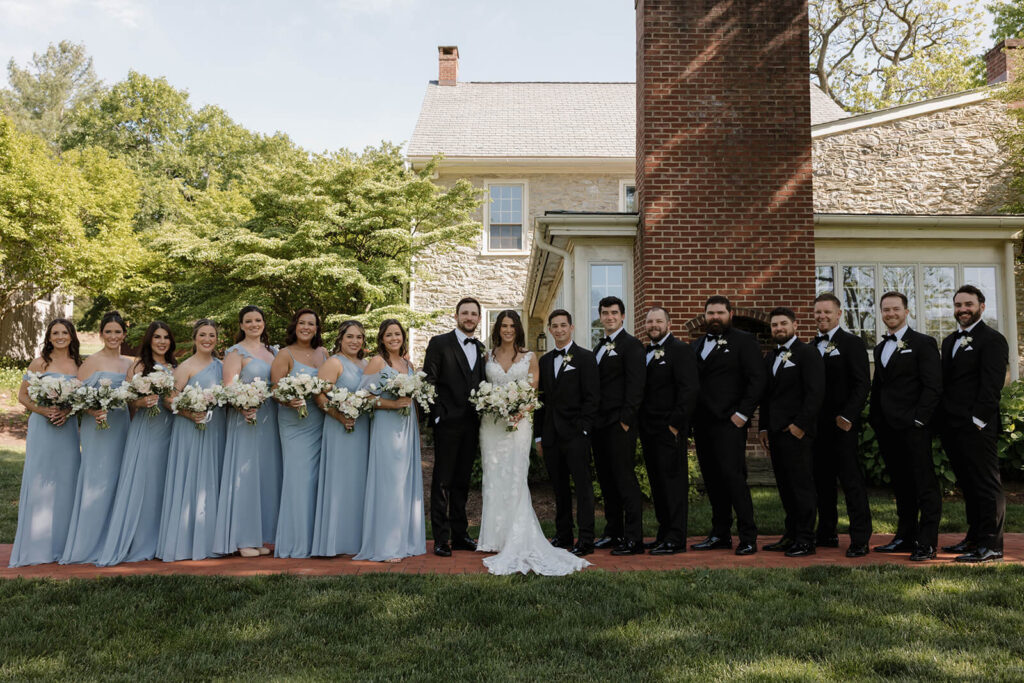 Bridal party in dusty blue dresses and groomsmen wearing black and white suits