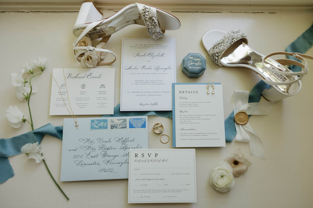 Elegant and classic wedding invitation suite with dusty blue envelope, ribbon, and gold wax seal
