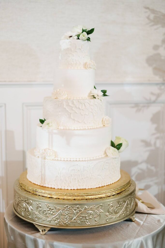 Elegant white five-tiered wedding cake on gilded stand