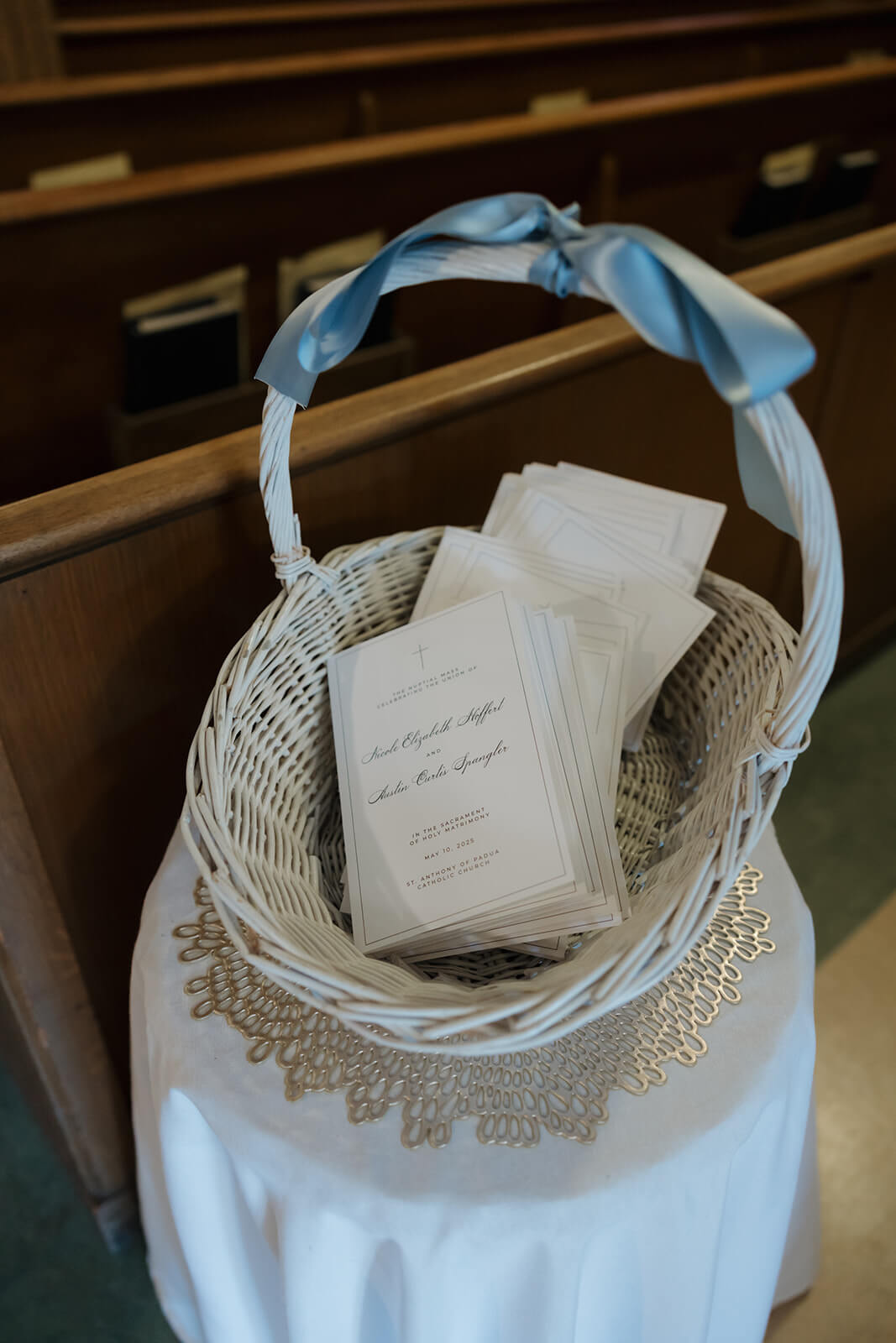 Wedding program booklets stacked in a white wicker basket