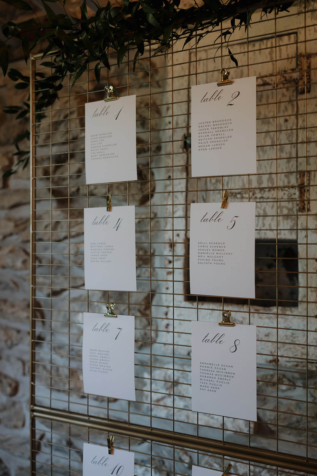 Gold wire frame seating chart display with table numbers and guests listed