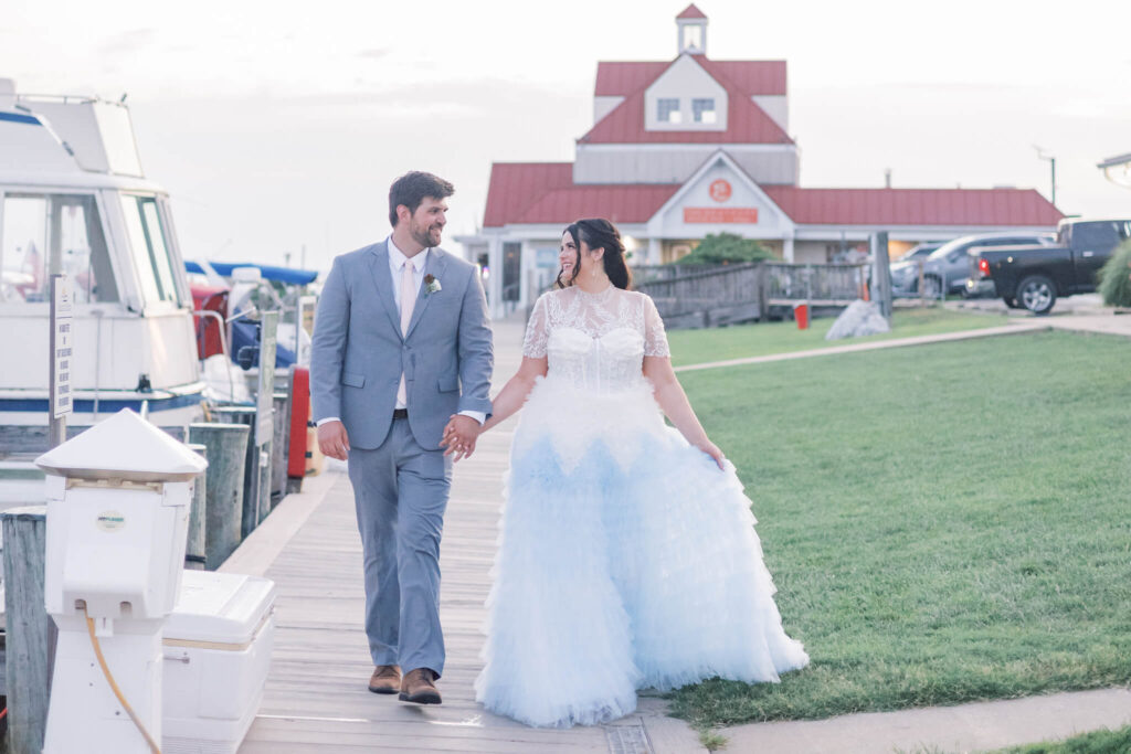 Bride and groom strolling hand in hand on a dock