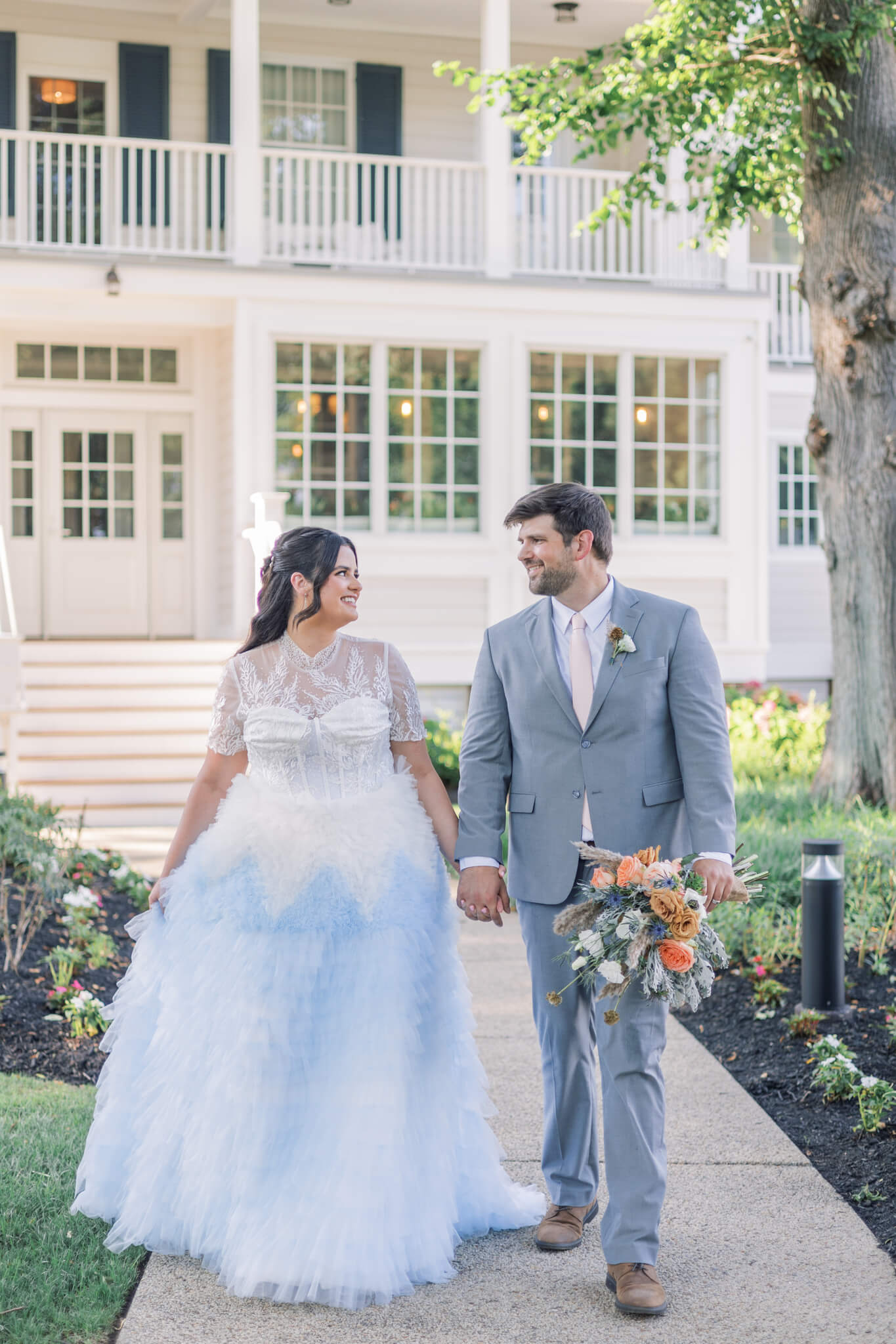 Bride dressed in coastal blue ombre wedding dress with groom dressed in gray suit with peach tie