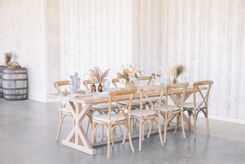Coastal chic wedding reception table adorned with peach flowers and natural grasses