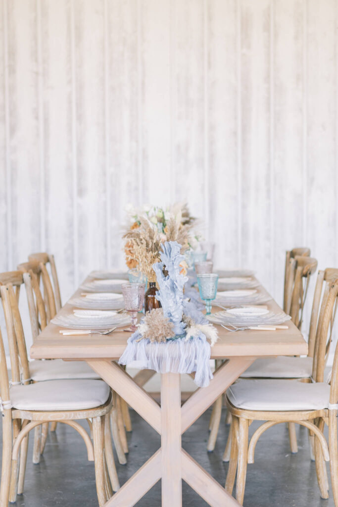 Coastal inspired wedding reception table with coral details and pastel glassware