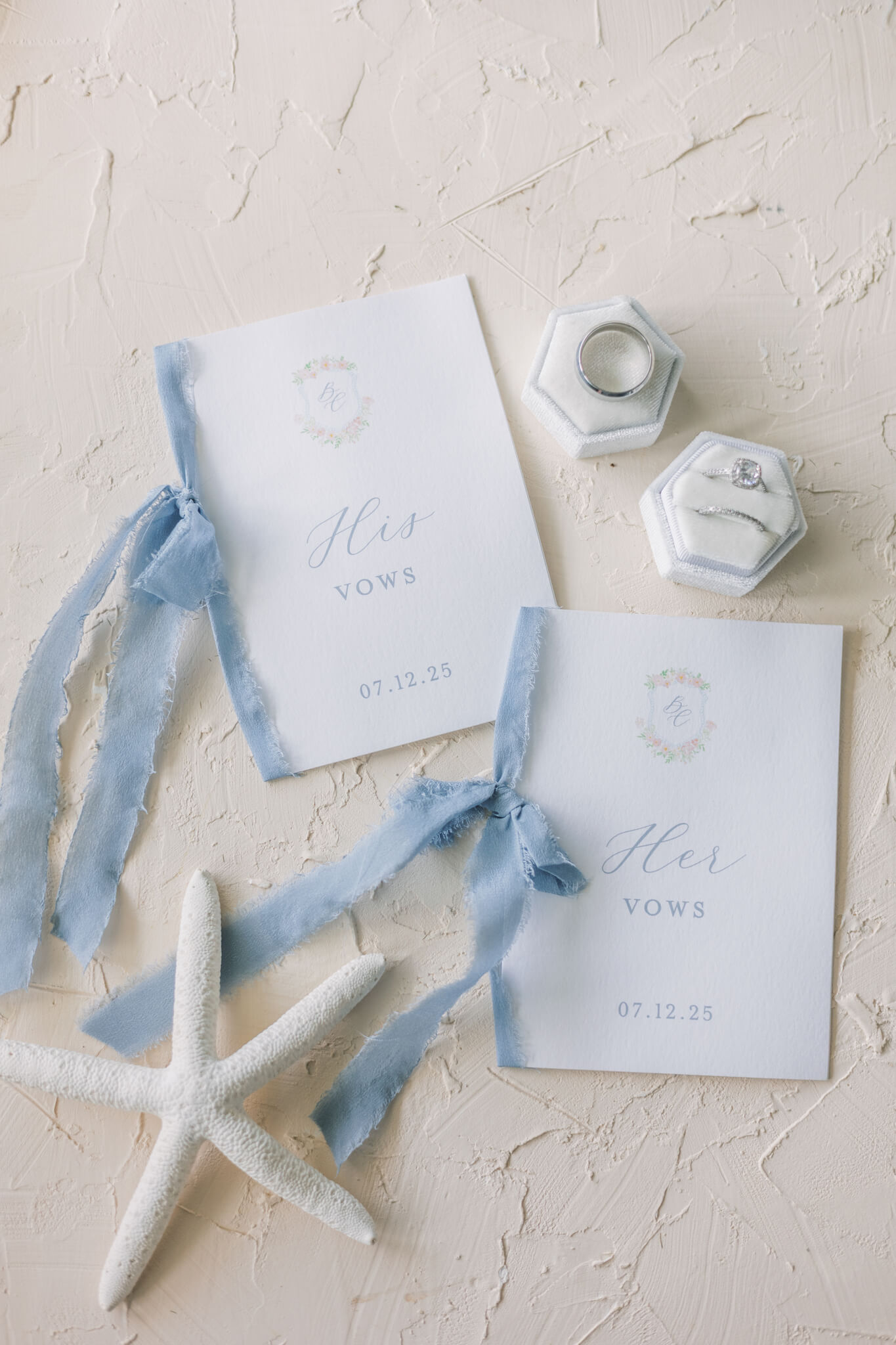 Custom his and hers wedding vow books with watercolor floral monogram and blue ribbon