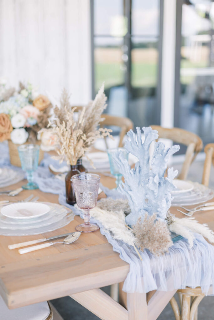 Coastal inspired wedding reception table with coral details and pastel glassware
