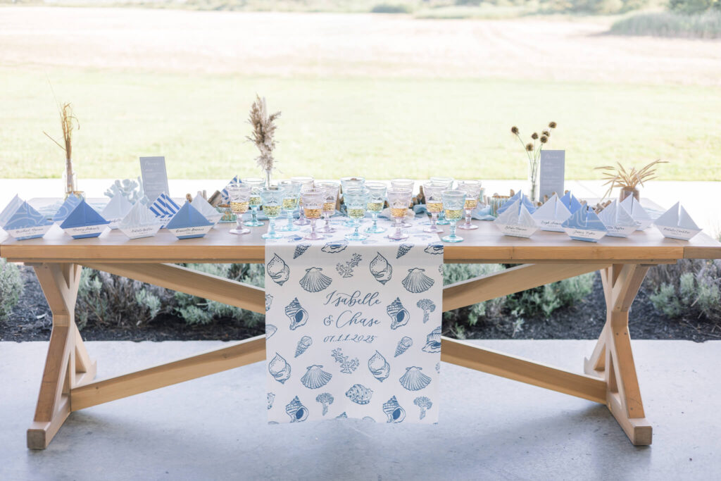 Wedding reception welcome table with custom seashell sign and pastel glassware