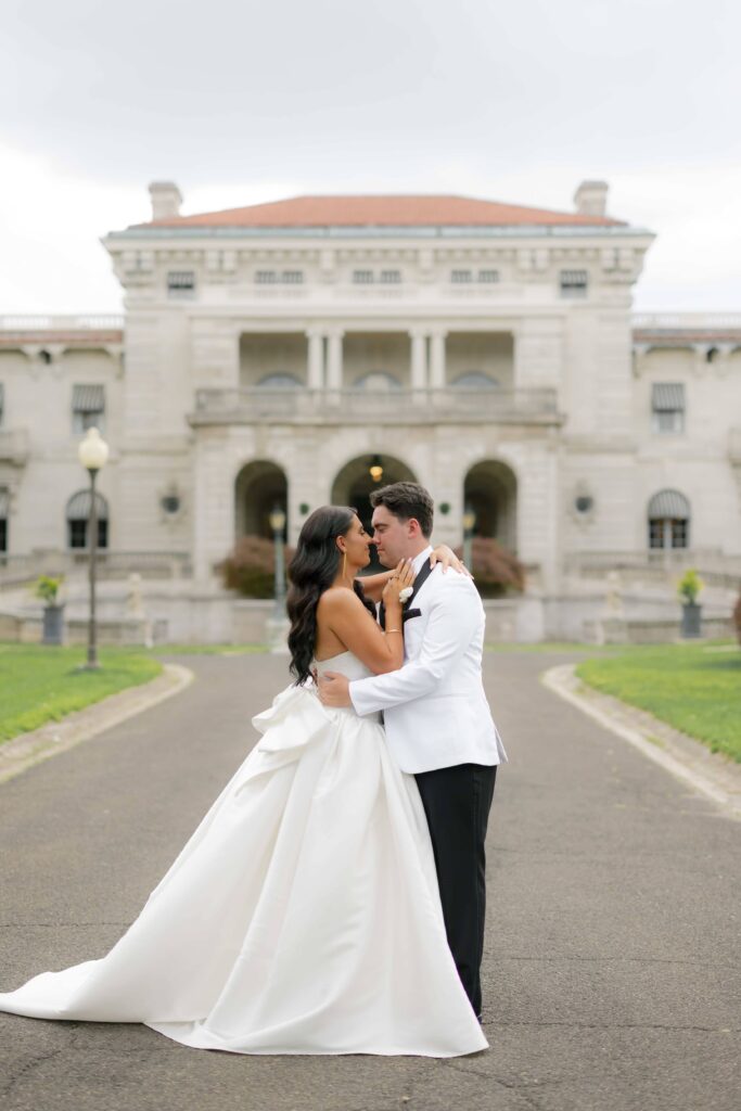 Bride and groom embrace in front of their wedding venue: Elstowe Manor at Elkins Estate