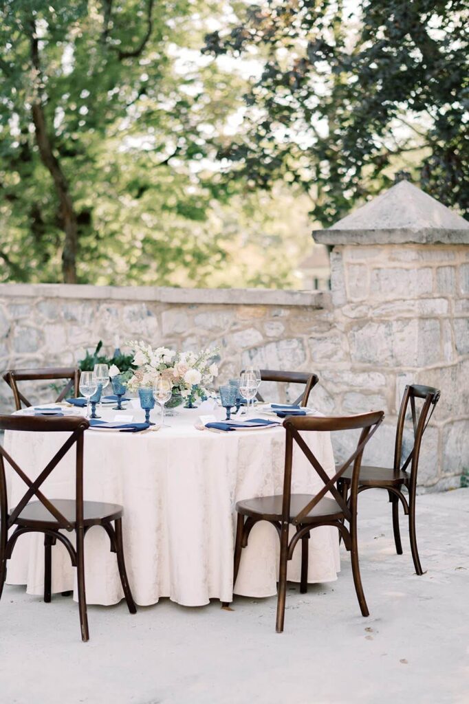Wedding reception table with cream tablecloth and elegant florals on the patio at Allenberry Resort