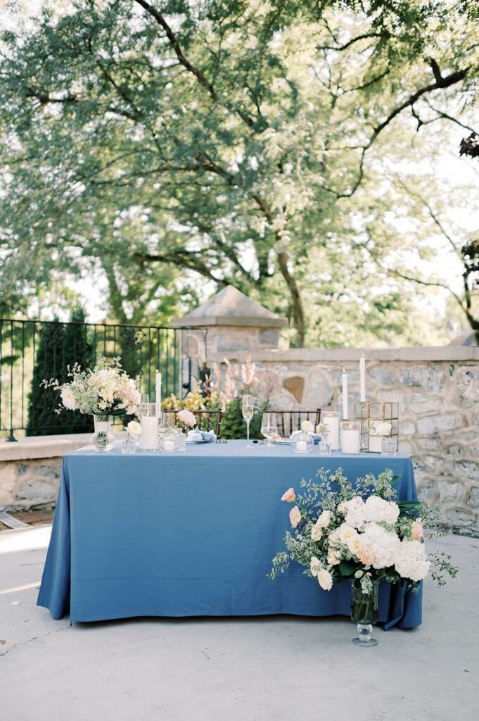 Sweetheart table with blue tablecloth and elegant florals on the patio at Allenberry Resort
