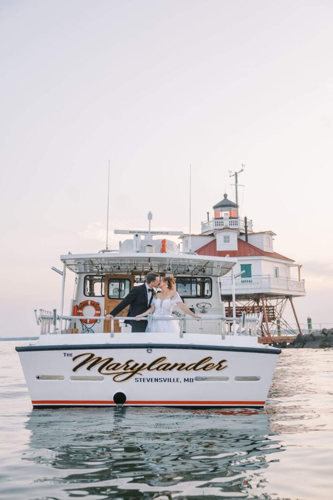 Bride and groom kiss on a boat that reads "The Marylander, Stevensville, Maryland"