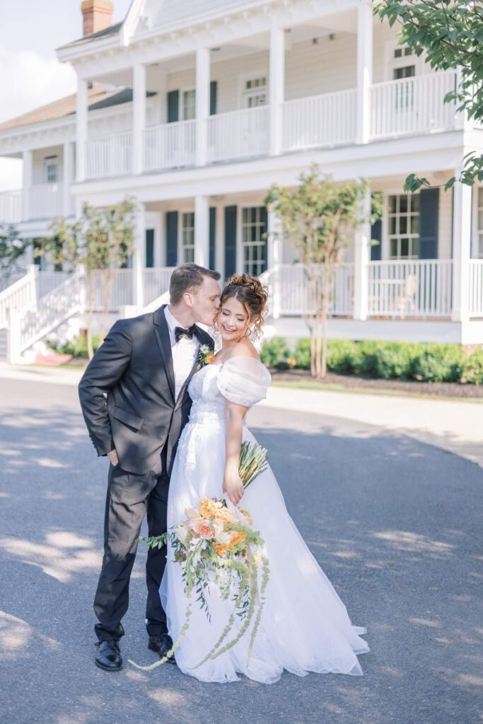 Groom kisses bride in front of Kent Island Resort, an east coast wedding venue