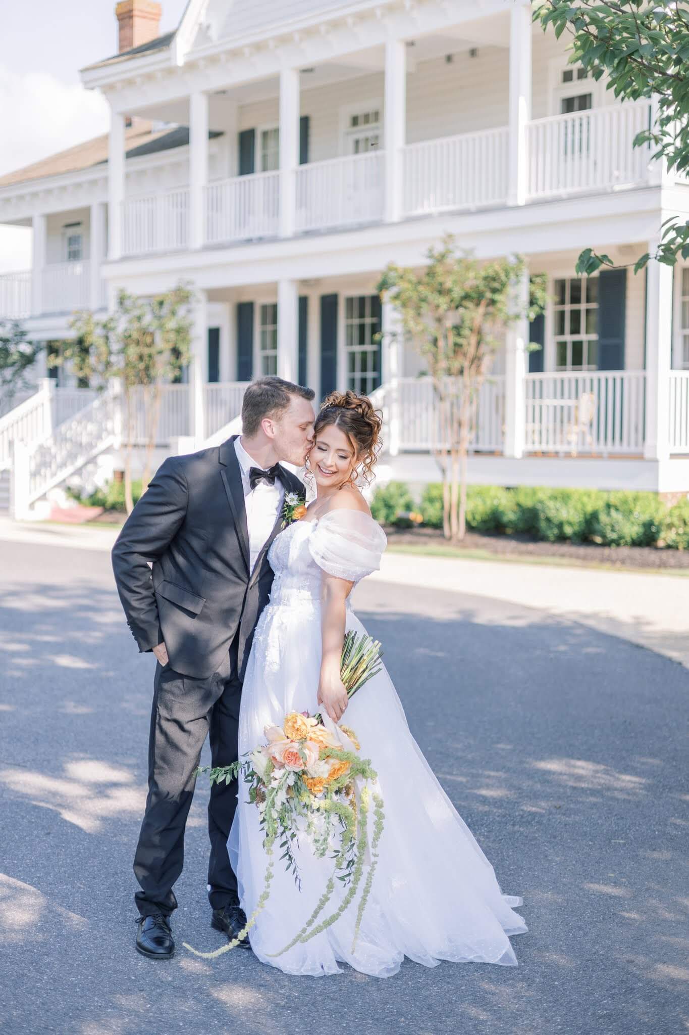 Groom kisses bride in front of Kent Island Resort, an east coast wedding venue