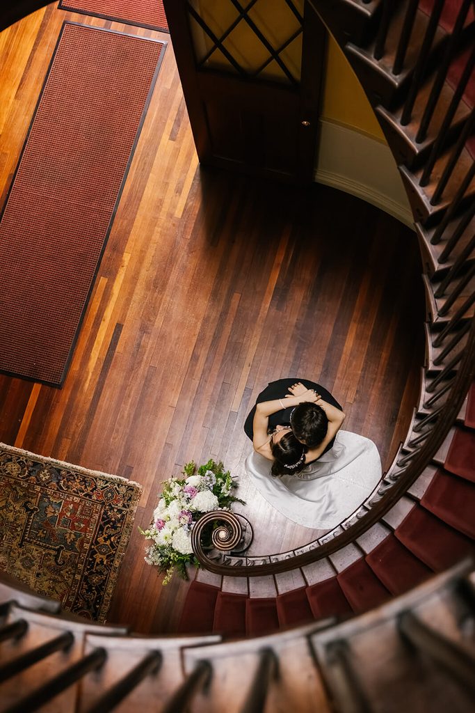 Bride and groom embracing by the staircase at Linden Place