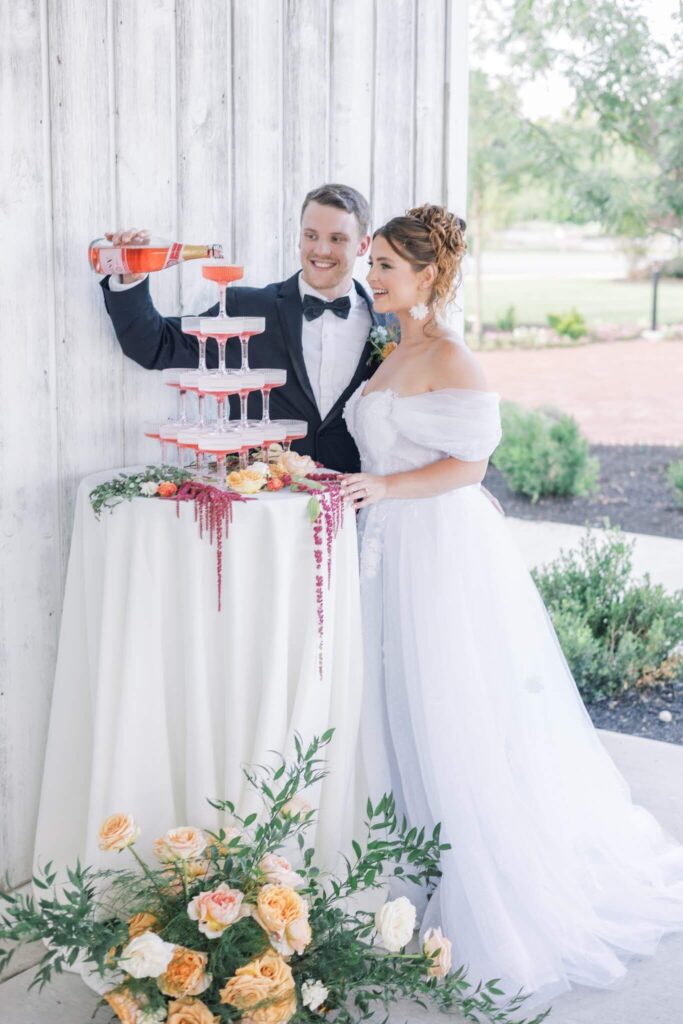 Groom pours strawberry champagne into a champagne tower