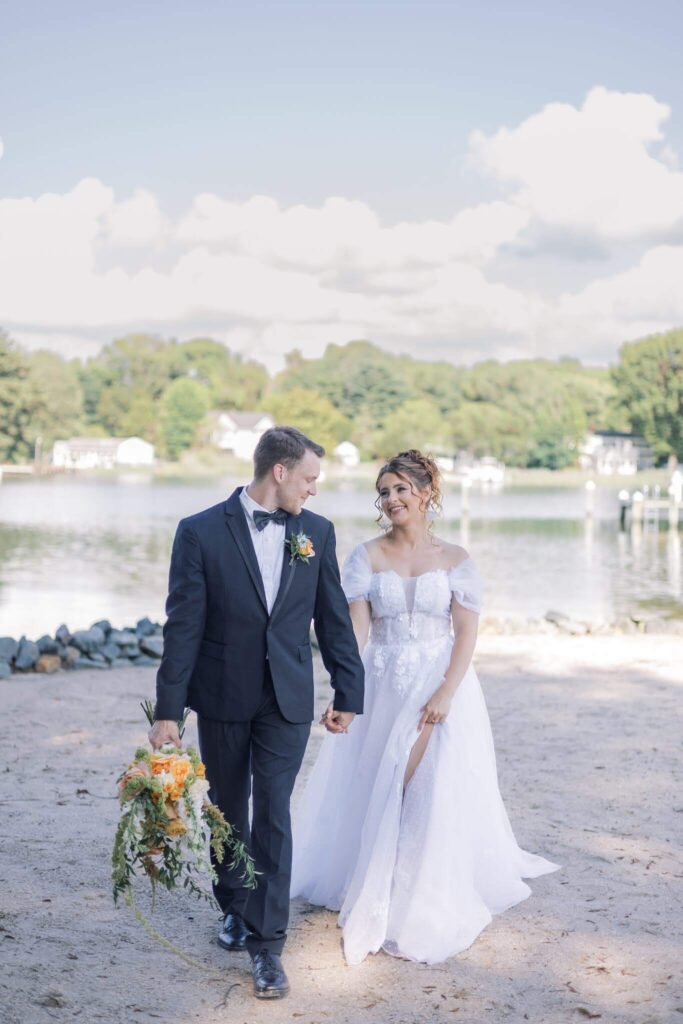 Bride and groom walk hand in hand on the shores at Kent Island Resort