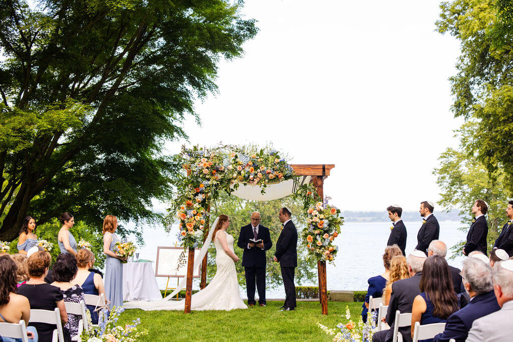 Bride and groom stand underneath a chuppah on the coast of Rhode Island