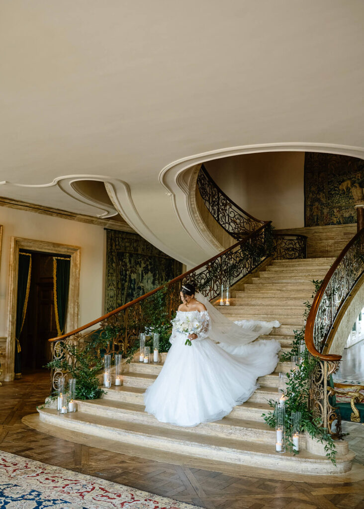 Bride in an elegant ballgown descends the main staircase at TPC Jasna Polana