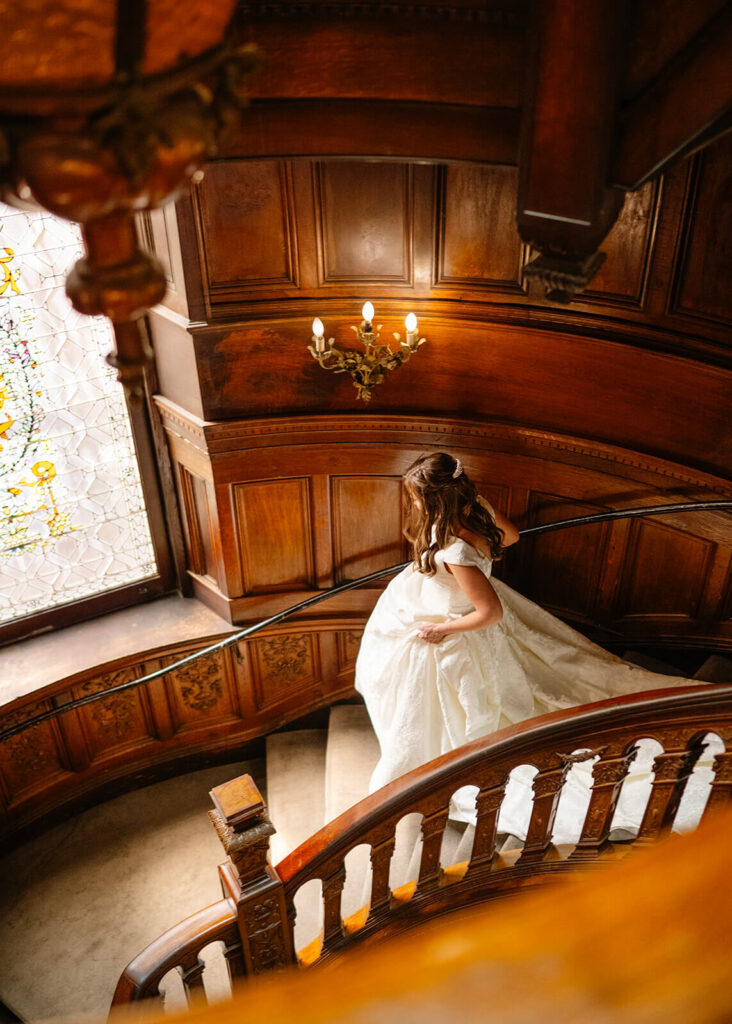Bride descends an ornate wood staircase at the Engineers Club