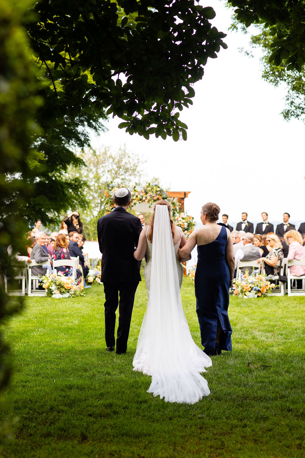 Mother and father of bride escort bride down the wedding aisle