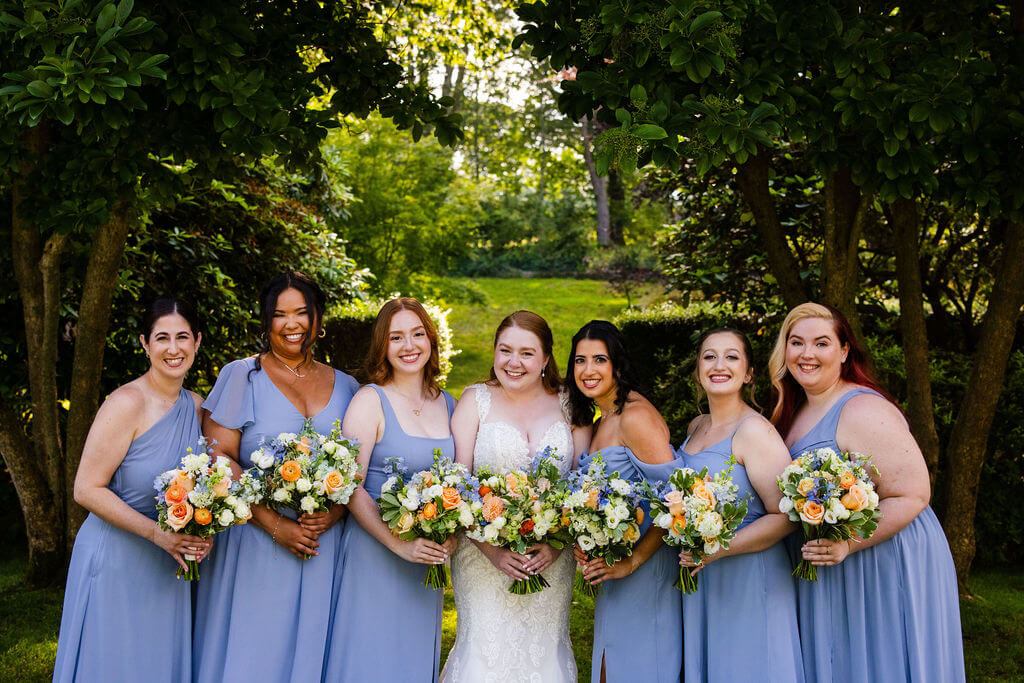 Bride with bridesmaids wearing periwinkle dresses and carrying bright bouquets