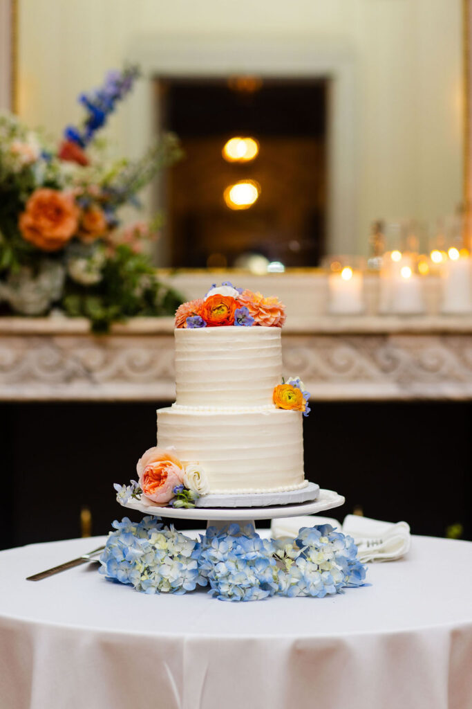 Two tiered white cake topped with colorful flowers