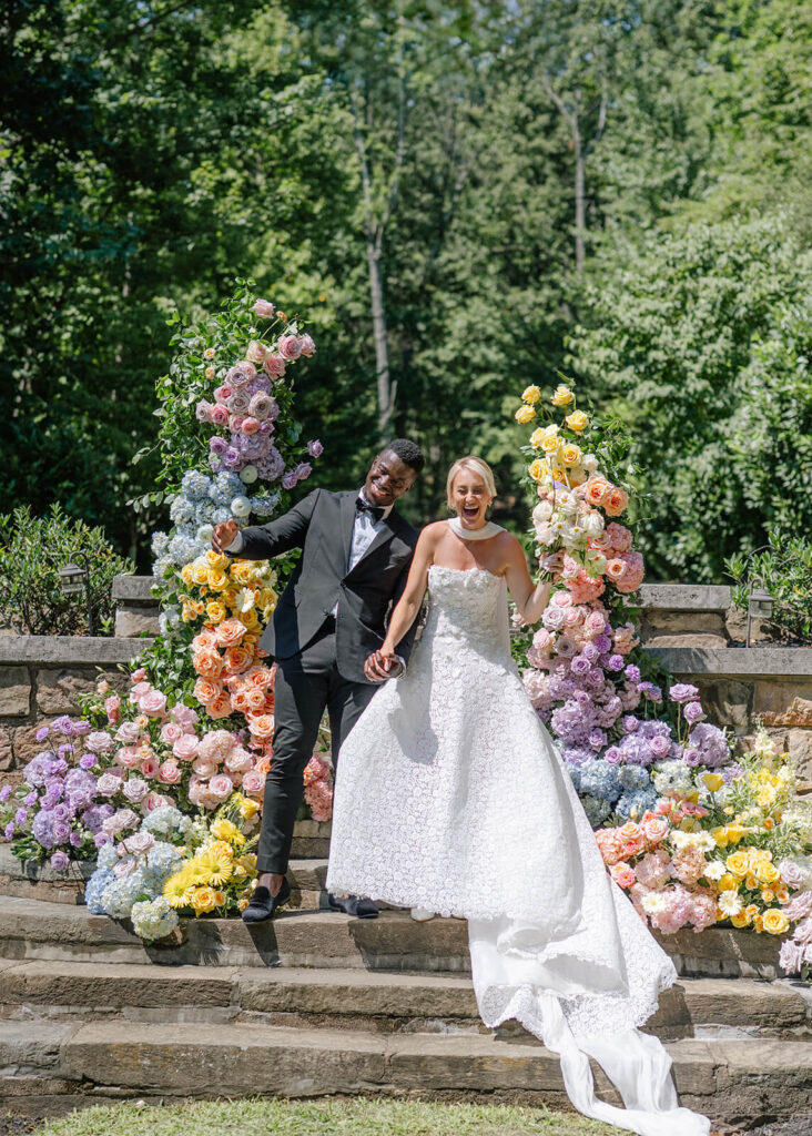 Bride and groom in front of a colorful deconstructed wedding arch during their wedding ceremony at Strong Mansion