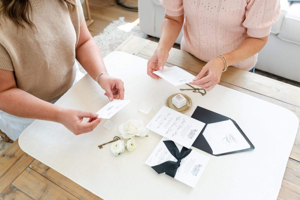 Heather Paperie co-owners discuss a client's custom invitation experience while looking at their wedding invitations