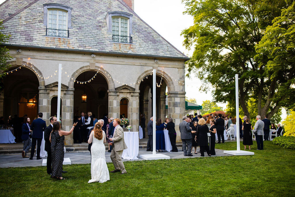 Guests enjoy cocktail hour on the patio at a summer wedding at Glen Manor House