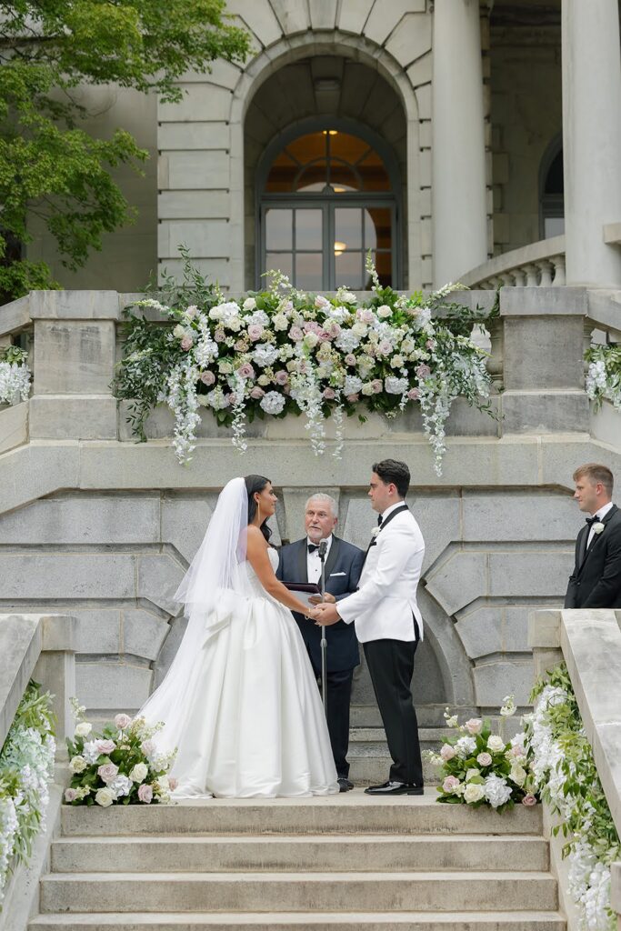 Bride and groom say their vows on the stairs of Elstowe Manor