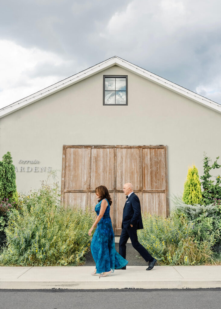 Guests walk by the exterior of East Coast wedding venue Terrain Gardens as they head to a wedding there