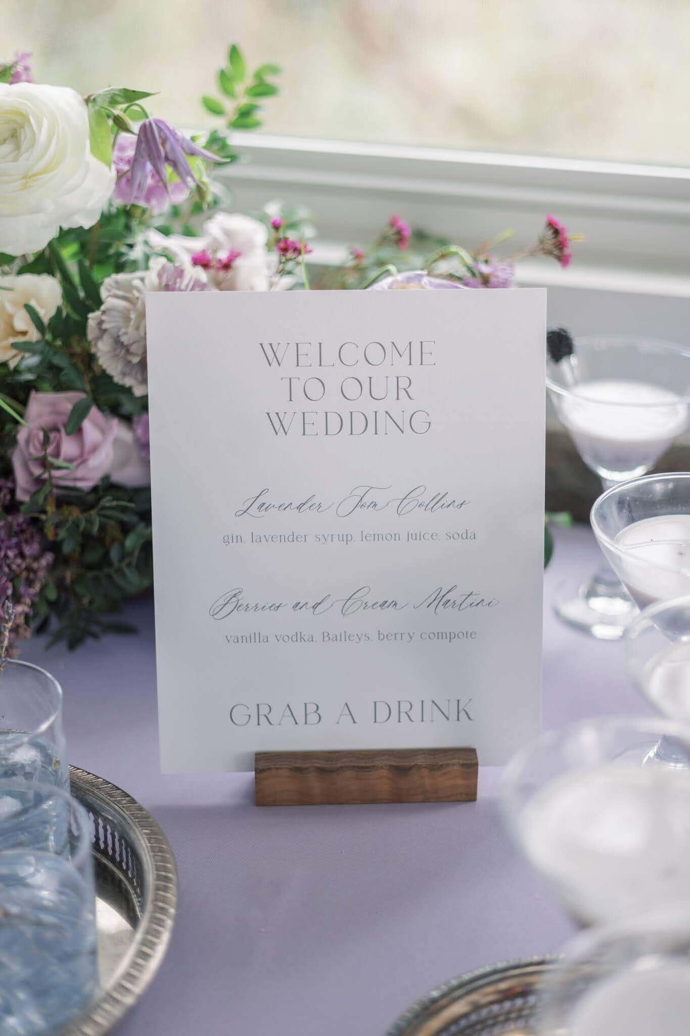 Lavender themed drink menu sign surrounded by cocktails on a table