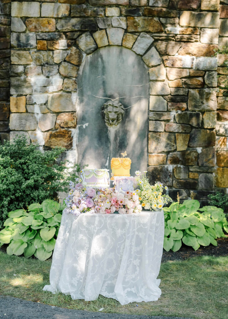 A wedding reception cake table with pastel florals in purple, pink, and yellow