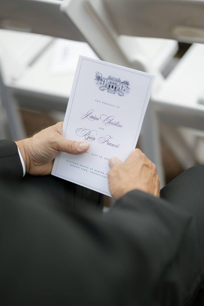 Wedding guest reading a wedding ceremony program booklet for a wedding at Elkins Estate