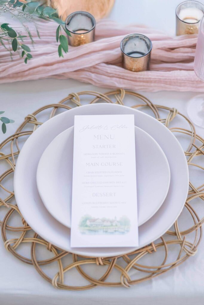 Wedding menu card with watercolor venue artwork sitting on a plate